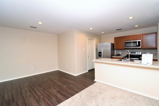 kitchen featuring dark wood-style flooring, a sink, visible vents, appliances with stainless steel finishes, and decorative backsplash