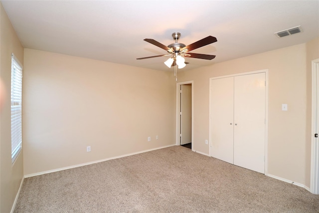 unfurnished bedroom featuring baseboards, visible vents, ceiling fan, carpet floors, and a closet