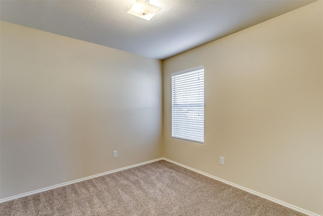 carpeted spare room with a textured ceiling and baseboards