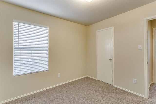 empty room featuring baseboards and light colored carpet