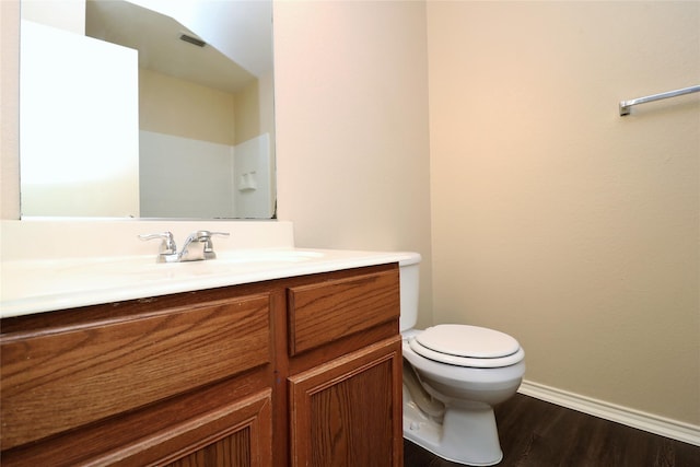 bathroom with baseboards, visible vents, toilet, wood finished floors, and vanity