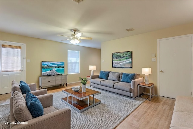 living room with light wood-style floors, visible vents, and ceiling fan