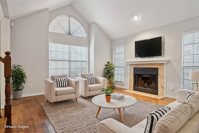 living area featuring lofted ceiling, a fireplace, baseboards, and wood finished floors