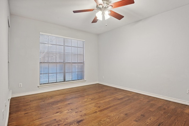 spare room featuring wood finished floors, a ceiling fan, and baseboards