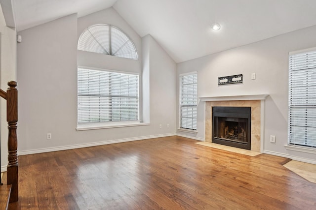 unfurnished living room with a fireplace, baseboards, vaulted ceiling, and wood finished floors