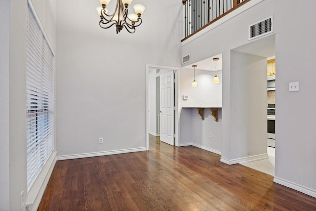 interior space with baseboards, visible vents, a chandelier, and wood finished floors