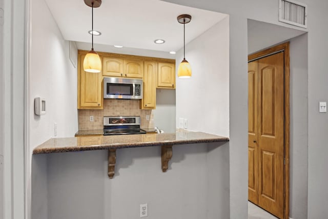 kitchen with visible vents, appliances with stainless steel finishes, stone counters, a kitchen bar, and backsplash