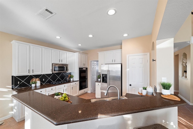 kitchen with light tile patterned floors, stainless steel appliances, a sink, visible vents, and tasteful backsplash