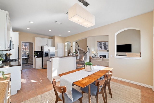 dining room with a fireplace, light tile patterned floors, recessed lighting, visible vents, and stairs