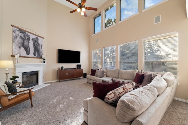 living room with a fireplace with raised hearth, plenty of natural light, visible vents, and carpet