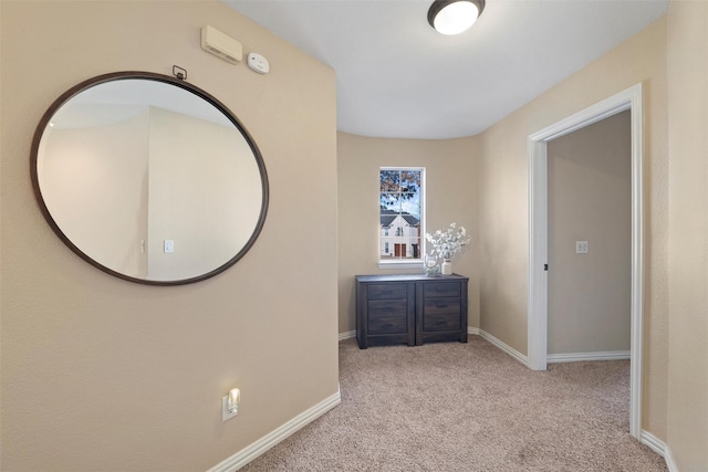 hallway featuring carpet flooring and baseboards