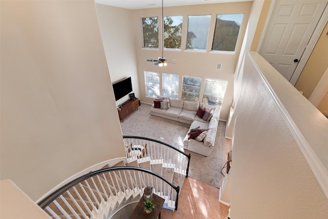 staircase featuring carpet floors, ceiling fan, a towering ceiling, and tile patterned floors