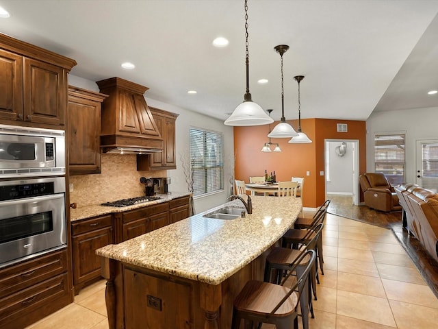 kitchen with light tile patterned floors, appliances with stainless steel finishes, a sink, custom exhaust hood, and backsplash