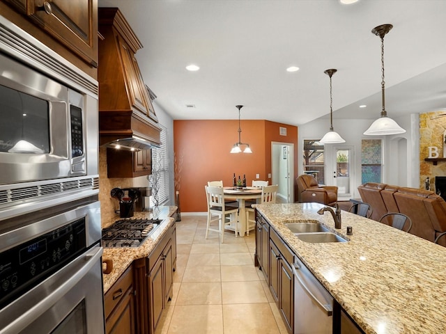 kitchen featuring light stone counters, light tile patterned flooring, stainless steel appliances, a sink, and pendant lighting