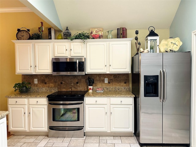 kitchen with white cabinets, light stone counters, stainless steel appliances, and backsplash