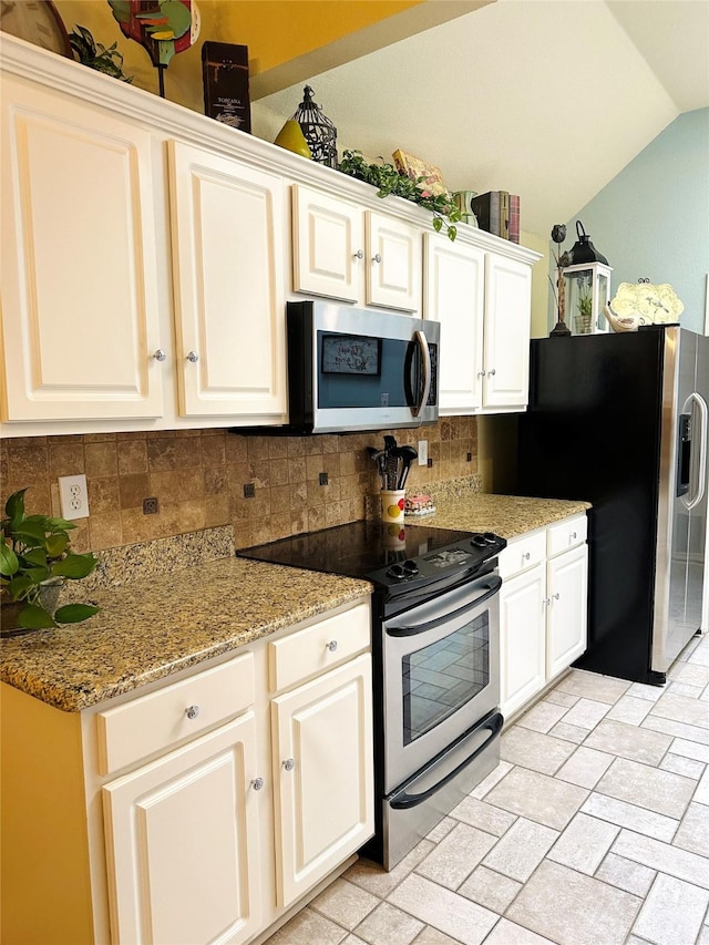 kitchen with light stone counters, stainless steel appliances, tasteful backsplash, white cabinets, and vaulted ceiling