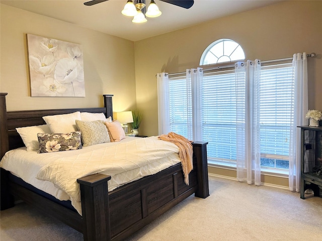 bedroom with a ceiling fan, light colored carpet, and baseboards