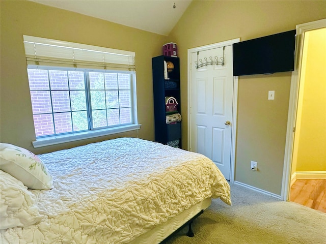 carpeted bedroom featuring lofted ceiling and baseboards