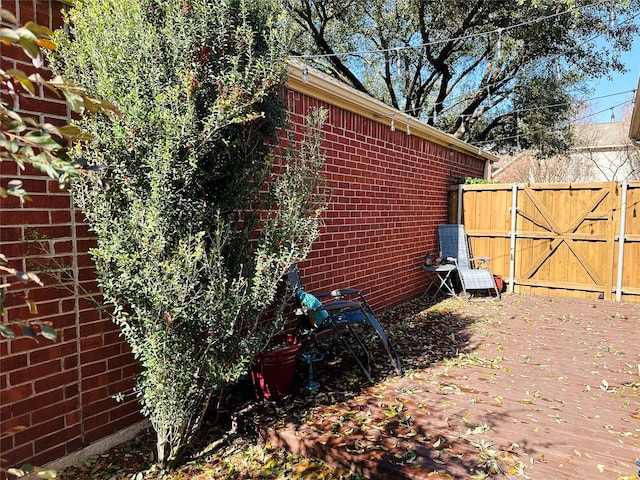 view of home's exterior featuring brick siding, fence, and a gate