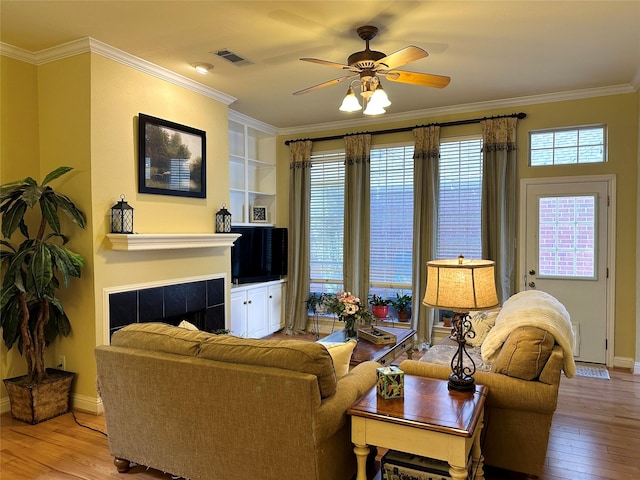 living area featuring a fireplace, visible vents, crown molding, and hardwood / wood-style floors