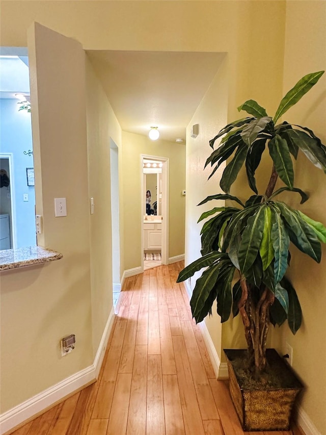 corridor with light wood finished floors and baseboards