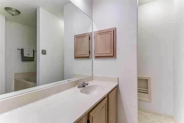 full bathroom with a textured ceiling, a bathtub, and vanity