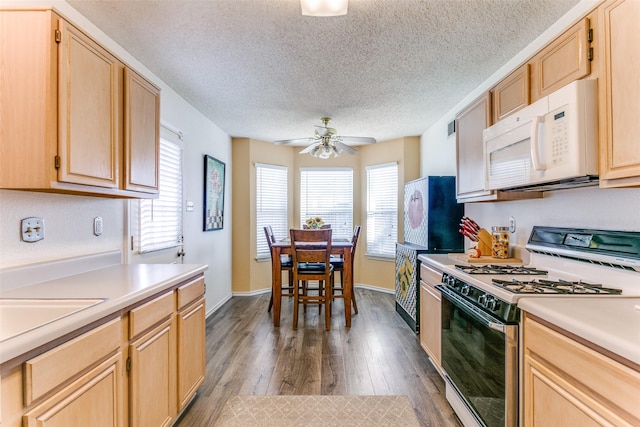 kitchen with gas range, light brown cabinets, white microwave, and light countertops