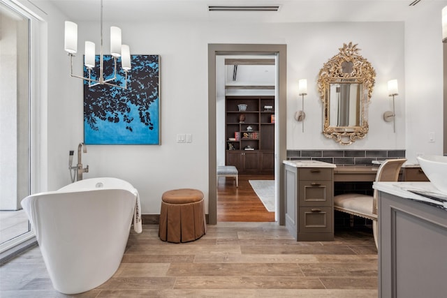 2300 Wolf St Unit 3D, Dallas, TX 75201 - bathroom with a notable chandelier, a soaking tub, visible vents, vanity, and wood finished floors