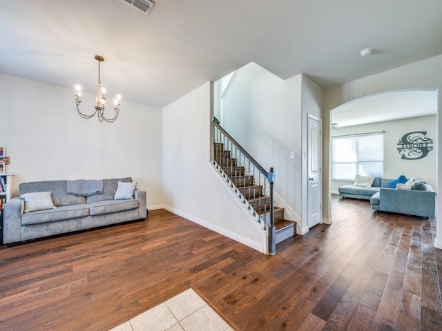 living room featuring arched walkways, visible vents, baseboards, stairs, and wood-type flooring