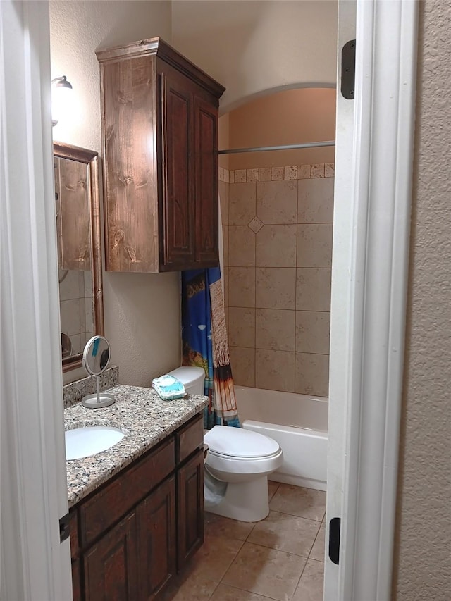 bathroom with tile patterned floors, toilet, shower / bath combo, vanity, and a textured wall