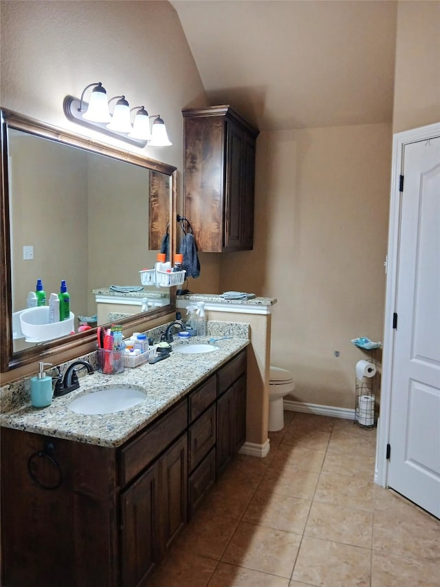 bathroom featuring tile patterned flooring, lofted ceiling, double vanity, and a sink