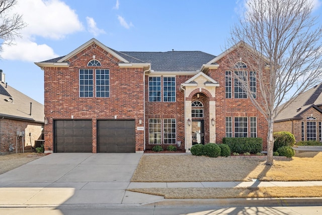 traditional-style house featuring central AC unit, concrete driveway, roof with shingles, an attached garage, and brick siding