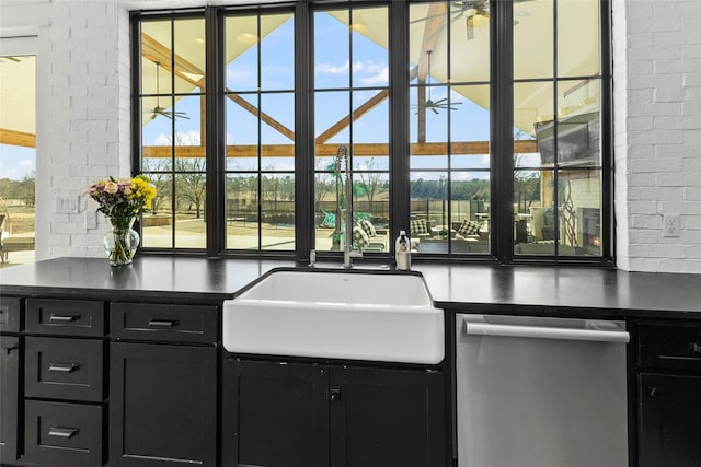 5949 County Road 137, Flint, TX 75762 - kitchen with stainless steel dishwasher, dark cabinets, a sink, dark countertops, and brick wall