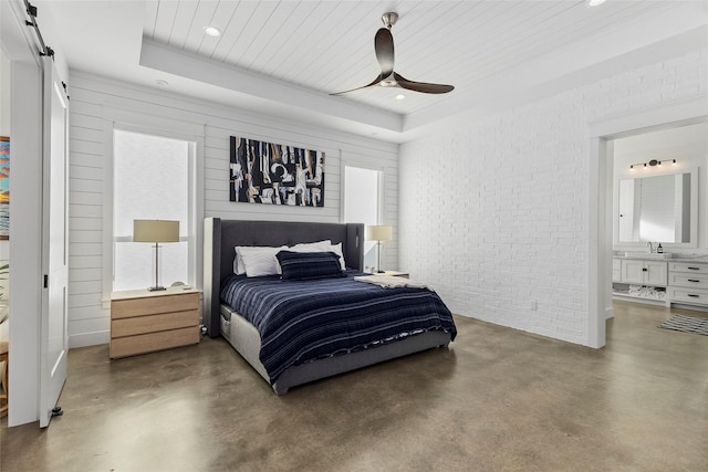 5949 County Road 137, Flint, TX 75762 - bedroom featuring a barn door, finished concrete floors, a raised ceiling, brick wall, and connected bathroom