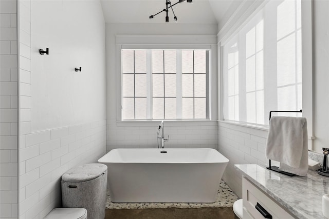 5949 County Road 137, Flint, TX 75762 - full bath featuring toilet, tile walls, a freestanding tub, lofted ceiling, and a wainscoted wall