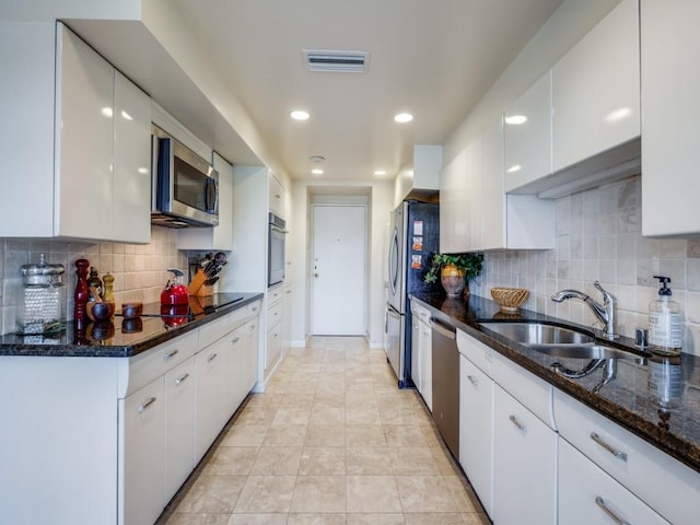 3525 Turtle Creek Blvd Unit 3D, Dallas, TX 75219 - kitchen featuring a sink, appliances with stainless steel finishes, white cabinetry, backsplash, and dark stone countertops