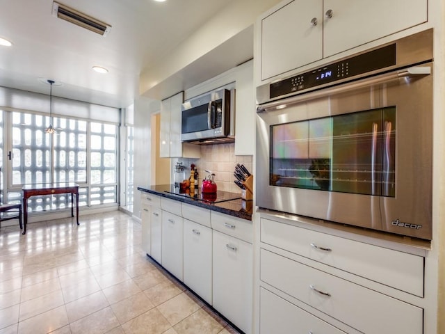 3525 Turtle Creek Blvd Unit 3D, Dallas, TX 75219 - kitchen featuring appliances with stainless steel finishes, tasteful backsplash, white cabinets, light tile patterned flooring, and recessed lighting