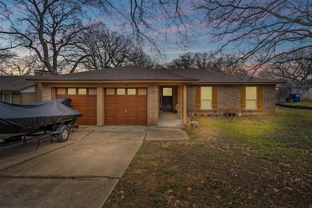 view of front of house with a garage, a shingled roof, concrete driveway, a yard, and brick siding