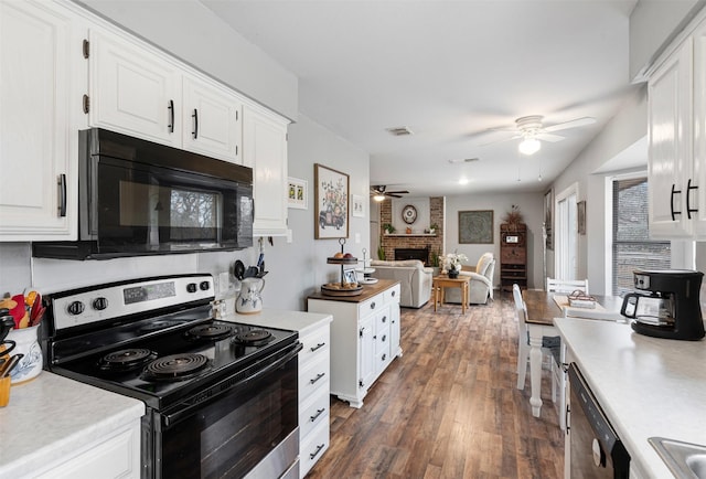 kitchen with visible vents, stainless steel electric stove, light countertops, a brick fireplace, and black microwave