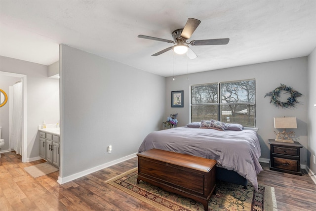 bedroom featuring baseboards, ceiling fan, ensuite bath, and light wood finished floors