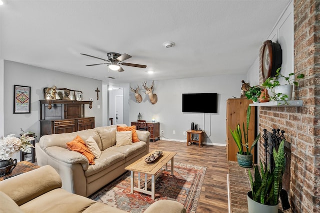 living area with ceiling fan, a fireplace, baseboards, and wood finished floors