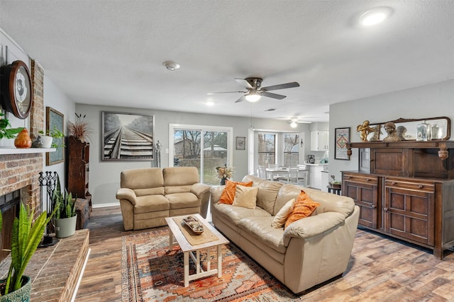 living room featuring a textured ceiling, a fireplace, light wood-style flooring, and baseboards