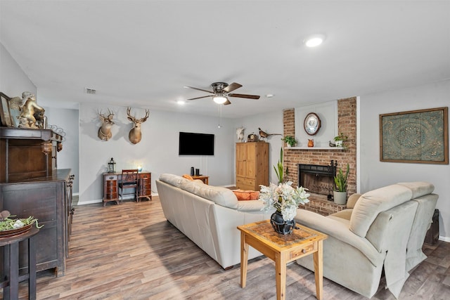 living room with a brick fireplace, wood finished floors, visible vents, and baseboards