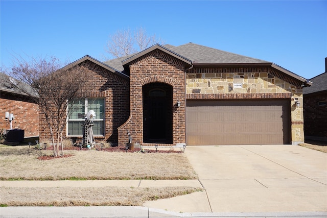 french provincial home featuring a garage, brick siding, concrete driveway, stone siding, and roof with shingles