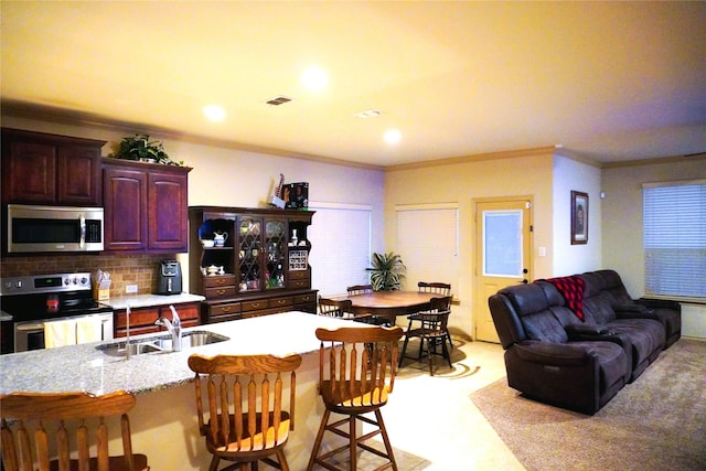 kitchen featuring a breakfast bar, tasteful backsplash, stainless steel appliances, and a sink