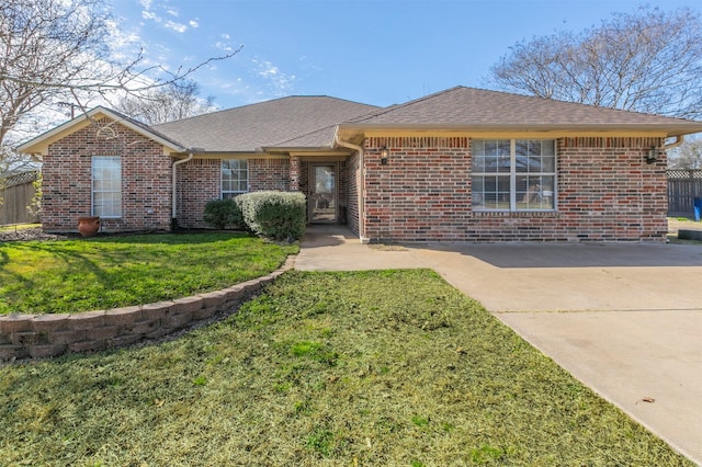 single story home with roof with shingles, fence, a front lawn, and brick siding