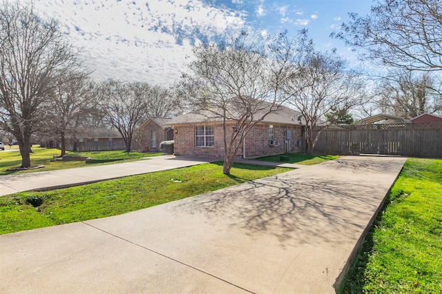 view of front facade with driveway, brick siding, a front lawn, and fence