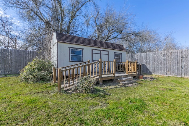 exterior space with an outbuilding, a yard, a shingled roof, and a fenced backyard