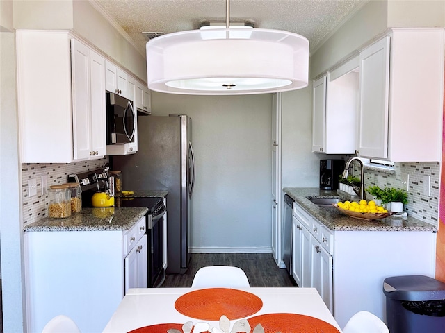 kitchen featuring a textured ceiling, white cabinetry, stainless steel appliances, and a sink