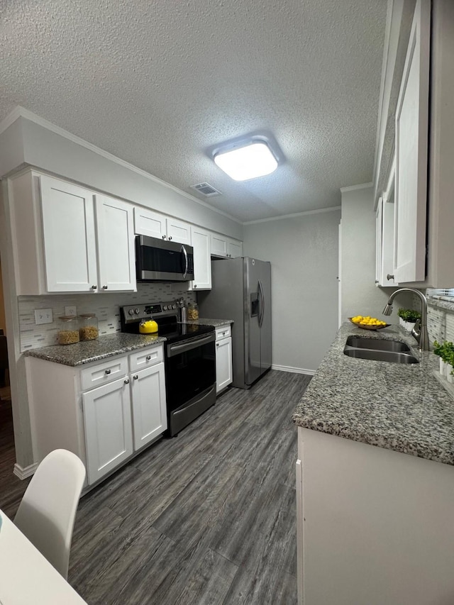 6503 Tempest Dr, Arlington, TX 76001 - kitchen featuring stainless steel appliances, a sink, ornamental molding, dark wood-style floors, and white cabinetry